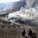 Residents look at burning houses in the village of Charektar outside the town of Kalbajar on November 14, 2020, during the military conflict between Armenia and Azerbaijan over the breakaway region of Nagorno-Karabakh. - Villagers in Nagorno-Karabakh set their houses on fire before fleeing to Armenia ahead of a weekend deadline that will see parts of the territory handed over to Azerbaijan as part of a peace agreement. (Photo by Alexander NEMENOV / AFP)