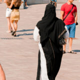 Muslim,Woman,Wearing,White,And,Black,Clothes,Going,Through,The