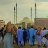 دوربین از پشت جمعی از مردم بلوچ را در حال راهپیمایی نشان میدهد. در افق دوردست مسجد مکی پیداست