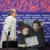 Actor Esmail Mehrabi walks past a photograph depicting Iranian actress and screenwriter Maryam Moghaddam (L) and Iranian film director and screenwriter Behtash Sanaeeha that is placed at their empty seats during a press conference for the film 'Keyke mahboobe man' (My favourite Cake) presented in competition during the 74th Berlinale, Europe's first major film festival of the year, in Berlin on February 16, 2024. The two Iranians said they have been barred from travelling to the Berlin film festival for their new movie's premiere for breaking one of their country's biggest taboos: showing a woman pursuing a "normal life". Maryam Moghaddam and Behtash Sanaeeha told AFP by video link from Tehran that they knew they were playing with fire with "My Favourite Cake", one of 20 films vying for the Golden Bear top prize. (Photo by Ronny HARTMANN / AFP)